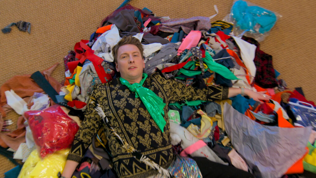 Presenter Joe Lycett in pile of fabric scraps